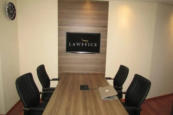 Sala de reuniões do seu Endereço Fiscal em Florianópolis na LAWFFICE, com mesa para quatro pessoas e TV com a marca LAWFFICE